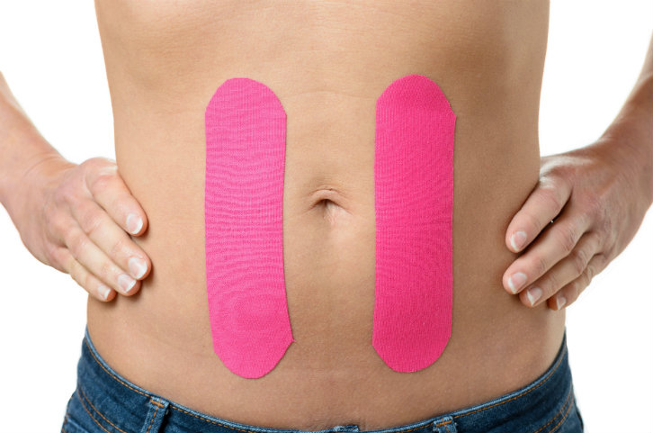 close up of woman with pink healing strips on her stomach