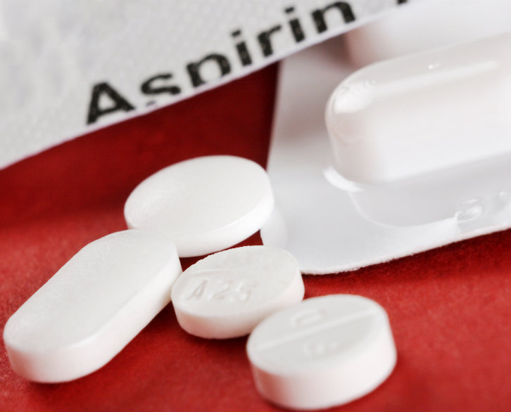 close-up of four white tablets with aspirin container